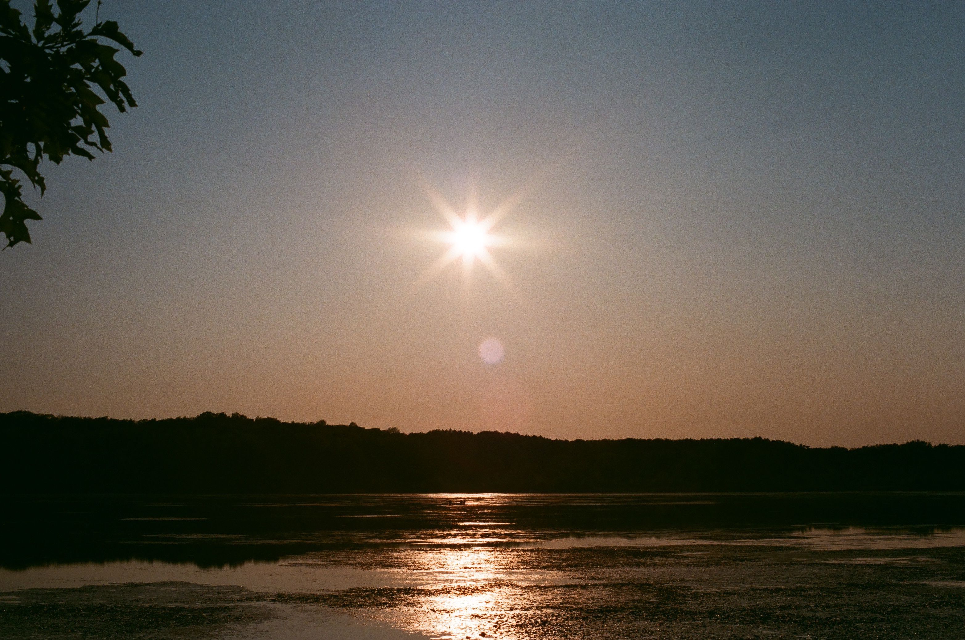 Breathtaking sunset over a calm lake and evergreen hills in Mendon Ponds Park, Rochester, New York