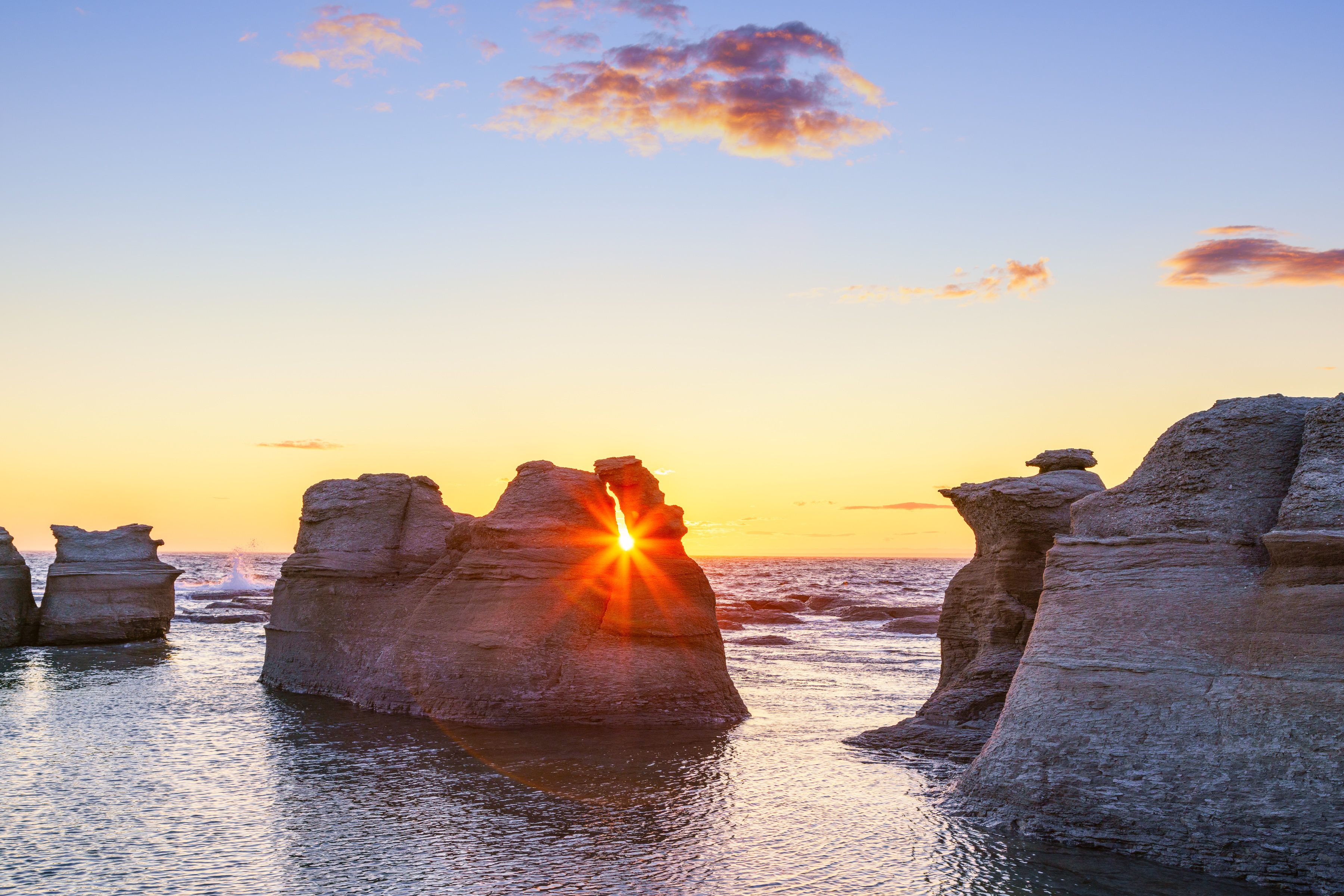 Un coucher de soleil sur une côte rocheuse, avec des formations rocheuses uniques.