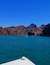 A boat on turquoise water with rocky cliffs in the background.