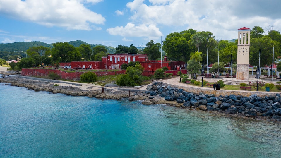 A coastal town with a prominent clock tower, red buildings, and a rocky shoreline.