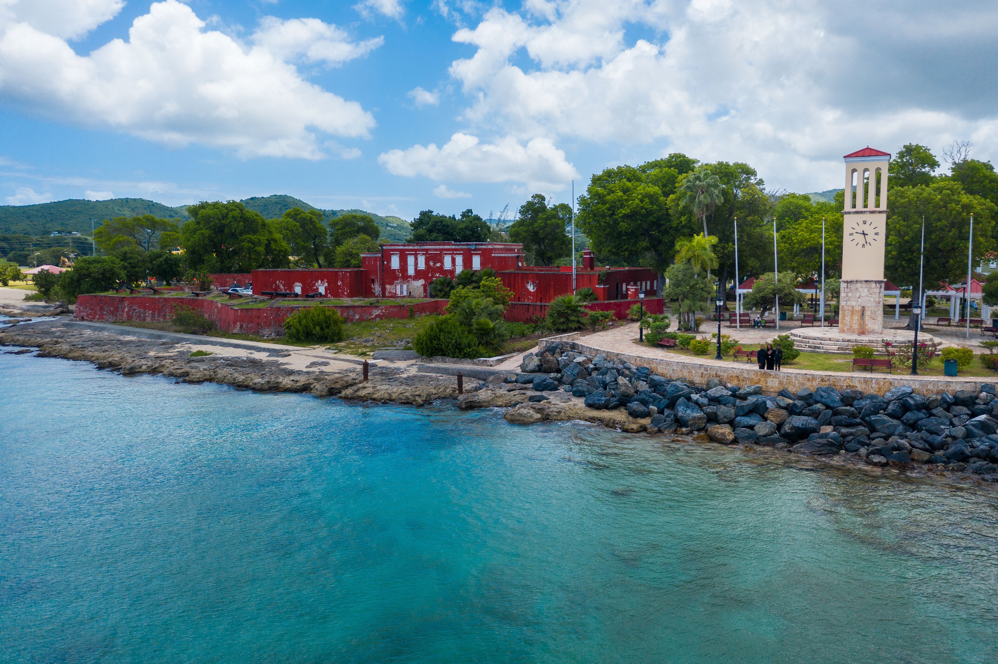 A coastal town with a prominent clock tower, red buildings, and a rocky shoreline.