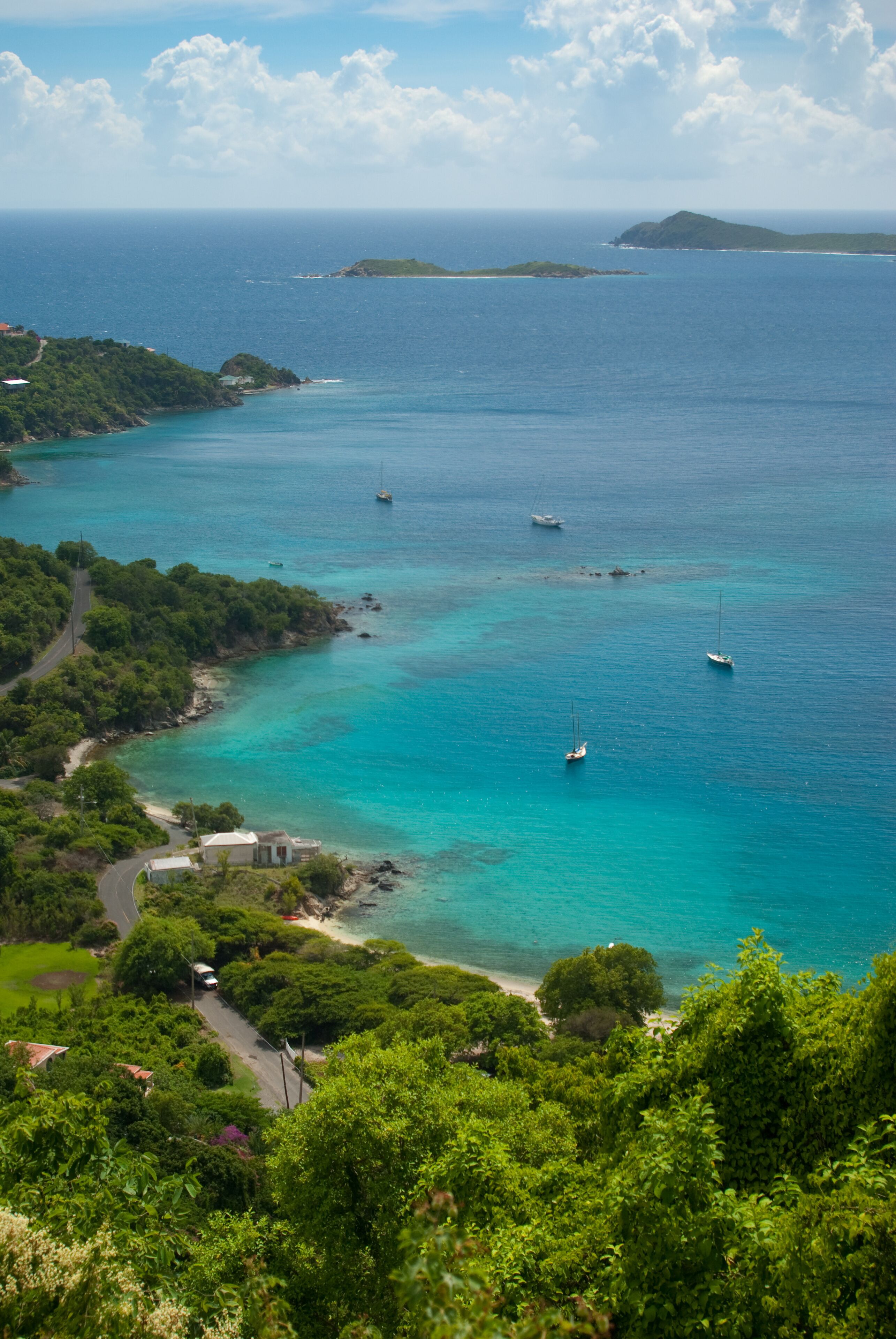 A coastal landscape with turquoise waters, boats, and lush greenery.