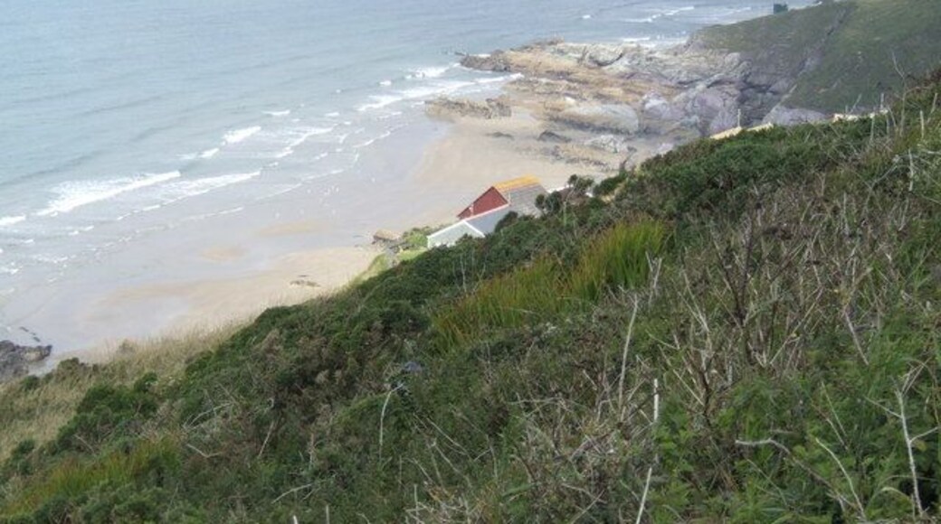 Freathy Cliff - view westwards The roof of a holiday home halfway down the slope can just be seen, with the rocks of Sharrow point beyond.