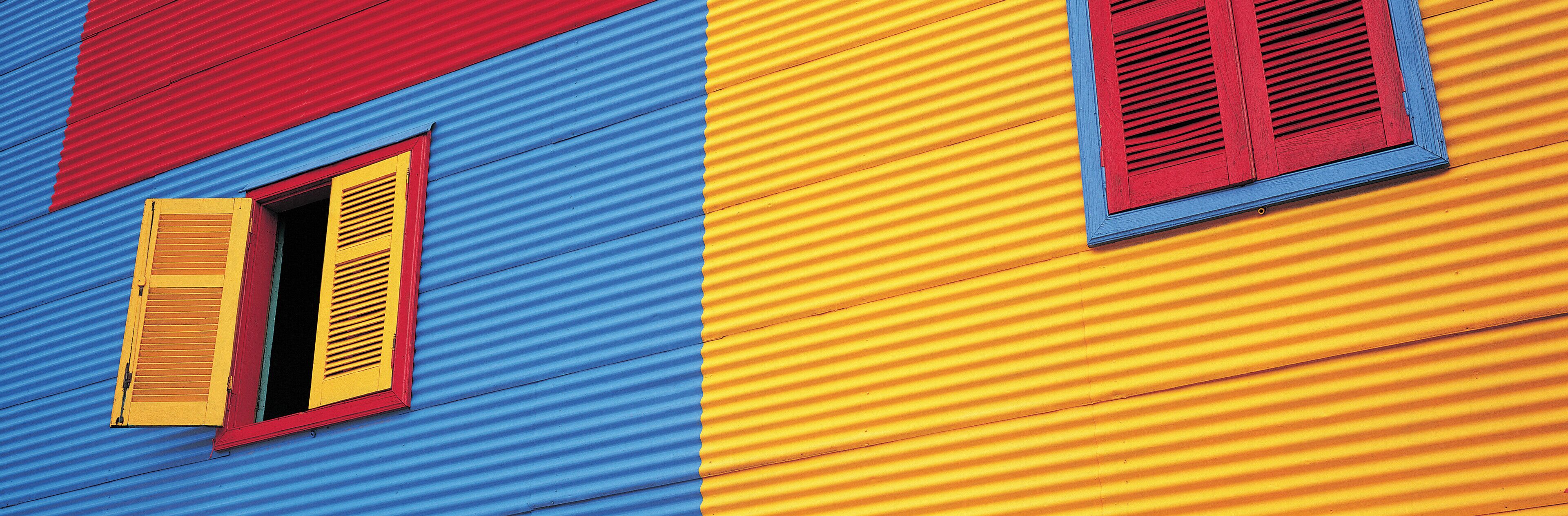 Ein farbenfrohes Gebäude mit blauen, roten und gelben Bereichen und Fensterläden.