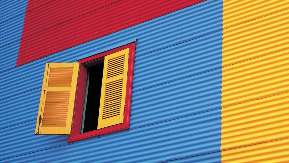 Ein farbenfrohes Gebäude mit blauen, roten und gelben Bereichen und Fensterläden.