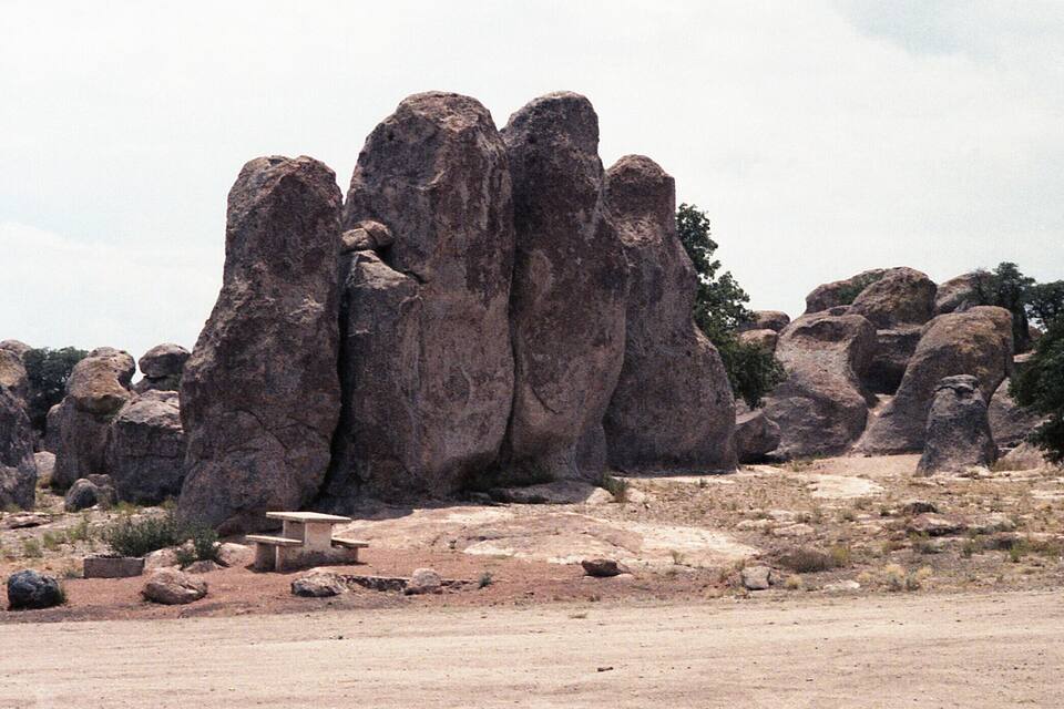 A rocky landscape with large boulders and a small stone bench.