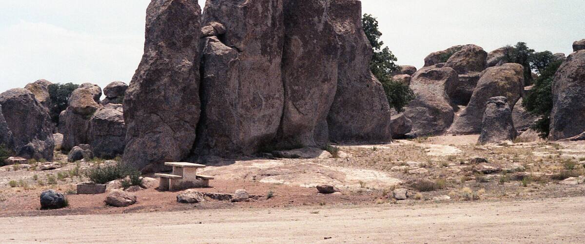A rocky landscape with large boulders and a small stone bench.