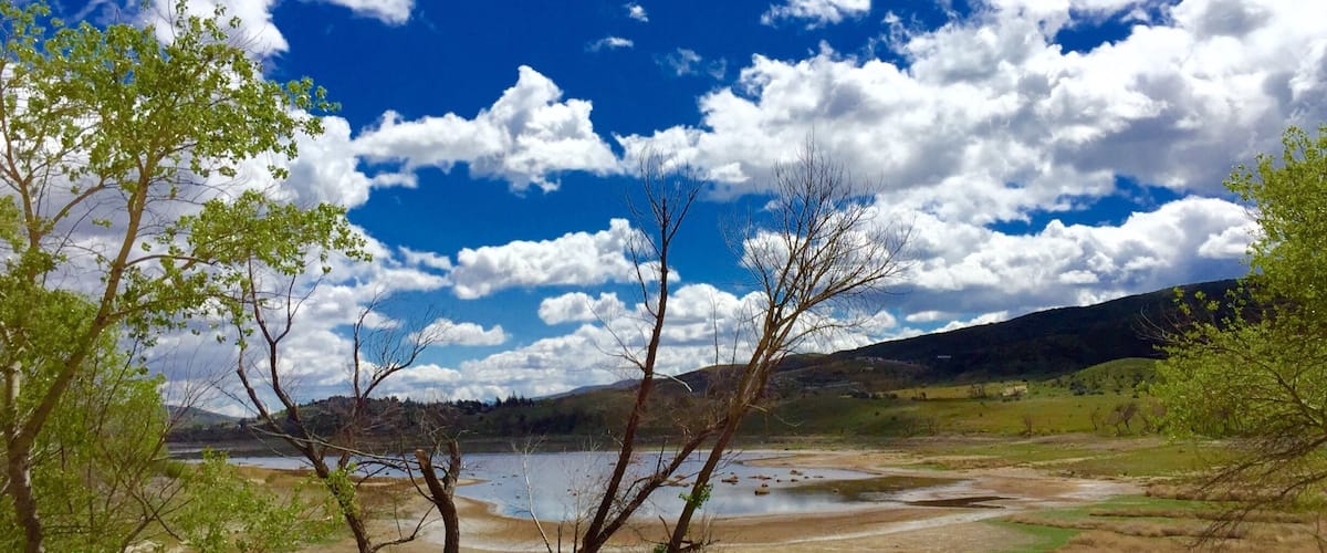A landscape with a lake, trees, and hills in the background.