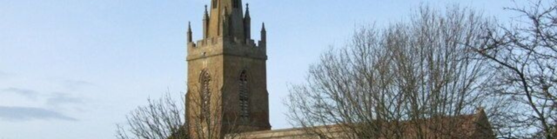 Uma igreja com uma torre alta e um cemitério à frente.