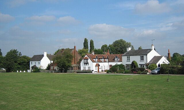 A row of white houses with red roofs in a rural setting.