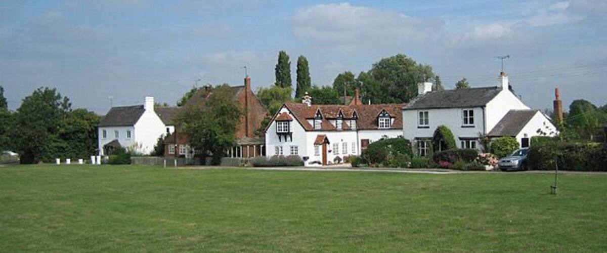 A row of white houses with red roofs in a rural setting.