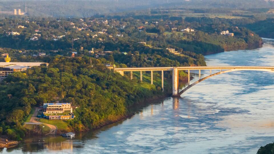 A river with a bridge, a town, and a hill with trees.