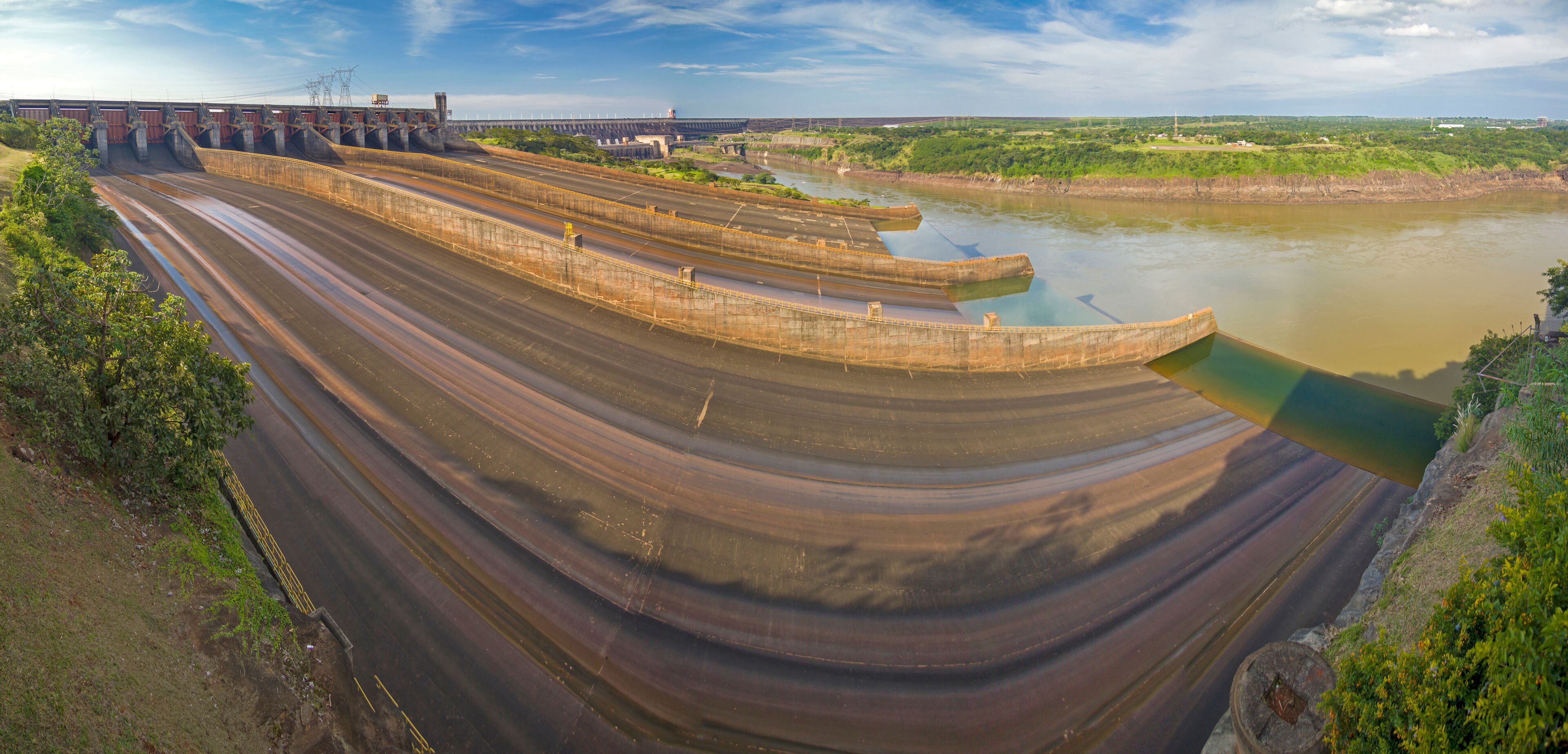 A large dam with multiple spillways and a river flowing through it.