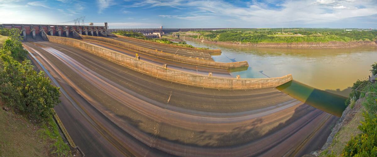 A large dam with multiple spillways and a river flowing through it.