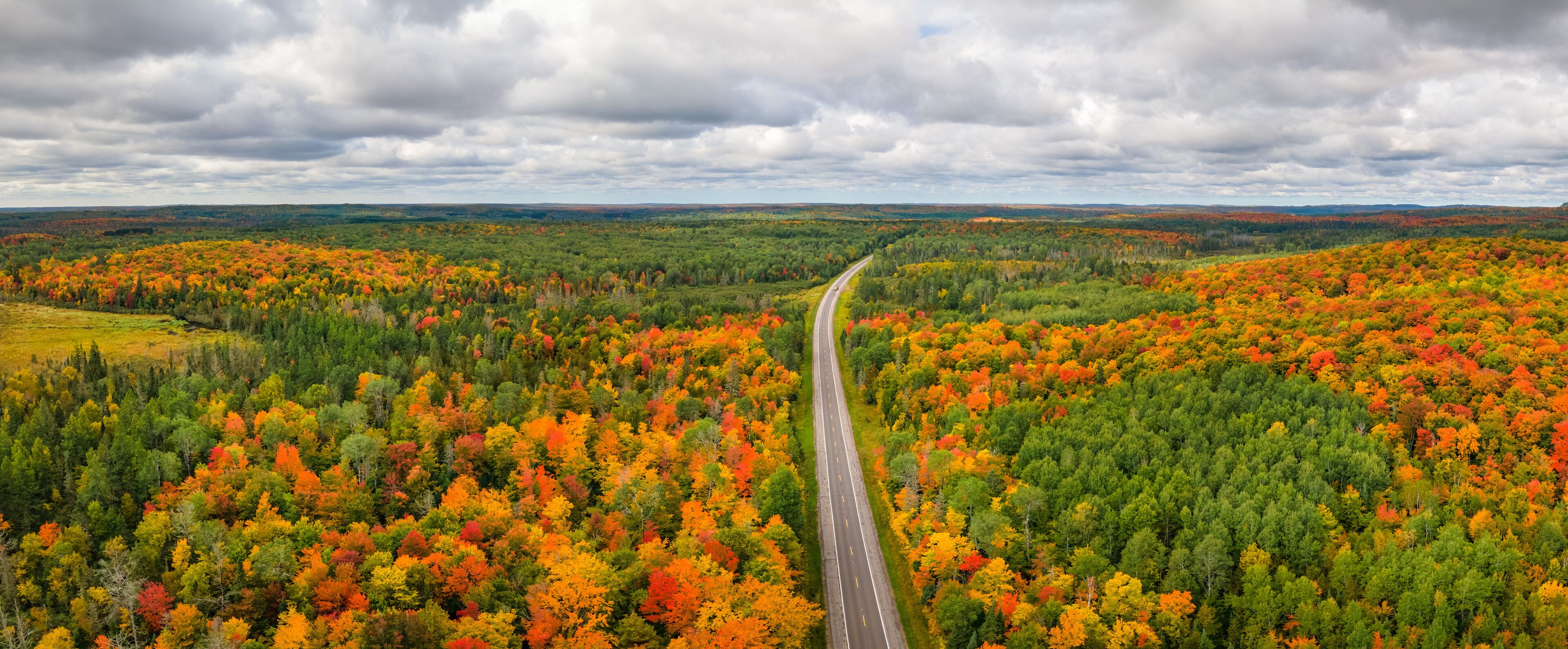A highway cutting through a forest with autumn foliage.