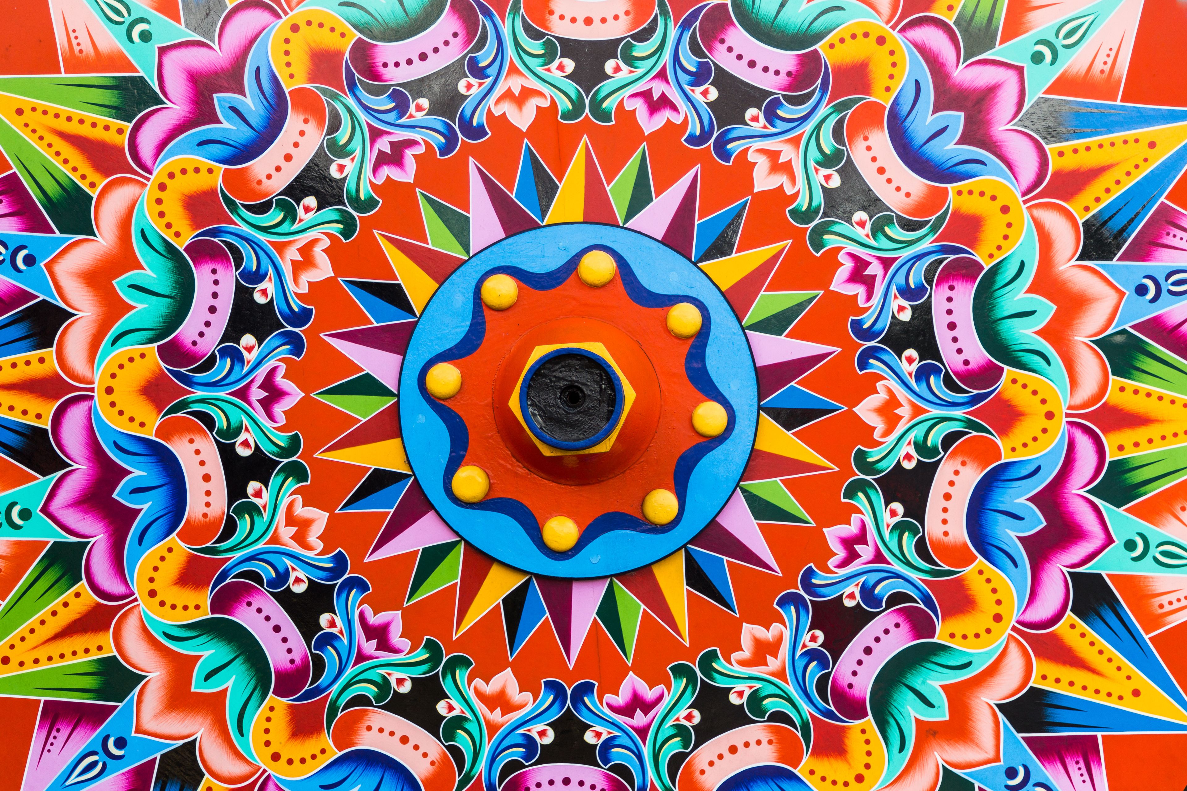 A colorful mandala pattern with a central circular design surrounded by intricate floral and geometric shapes.