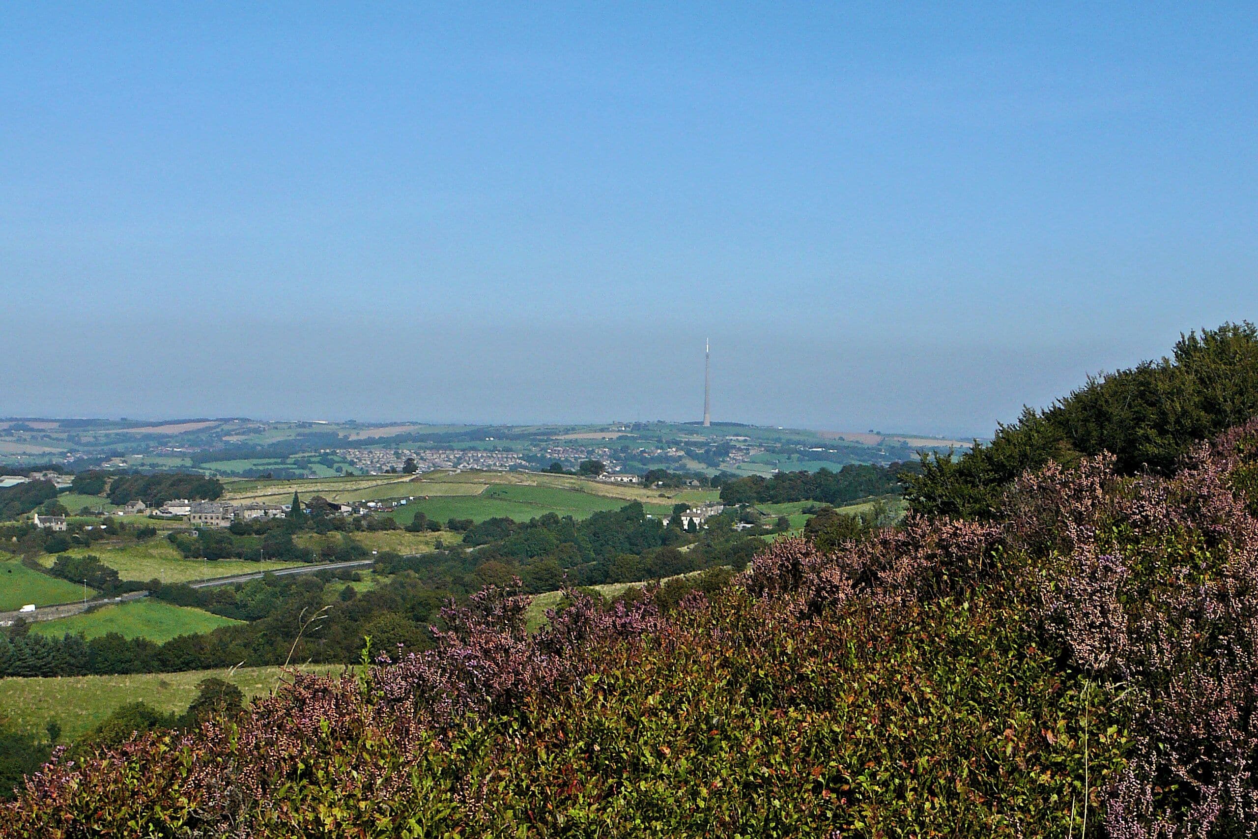 A rural landscape with rolling hills, a distant tower, and a village in the valley.
