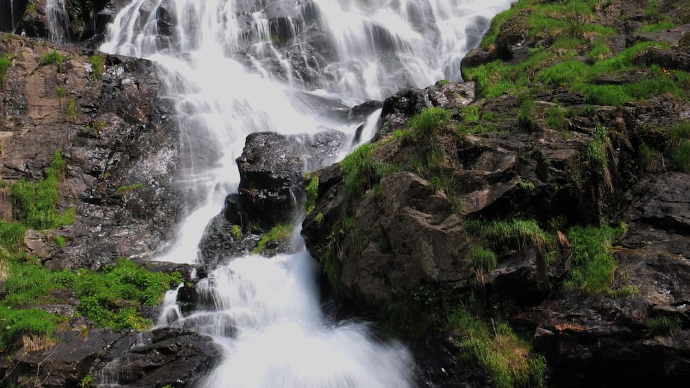 Une cascade spectaculaire, entourée d’un paysage rocheux et d’une végétation luxuriante.