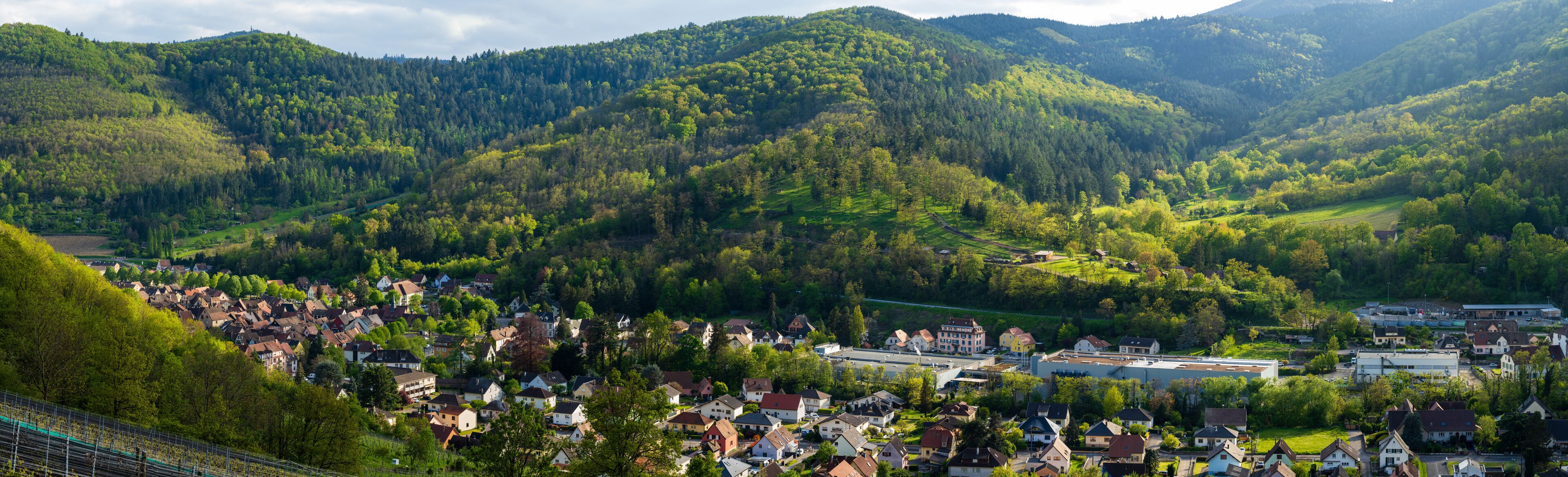 A village nestled in a valley surrounded by forested hills.