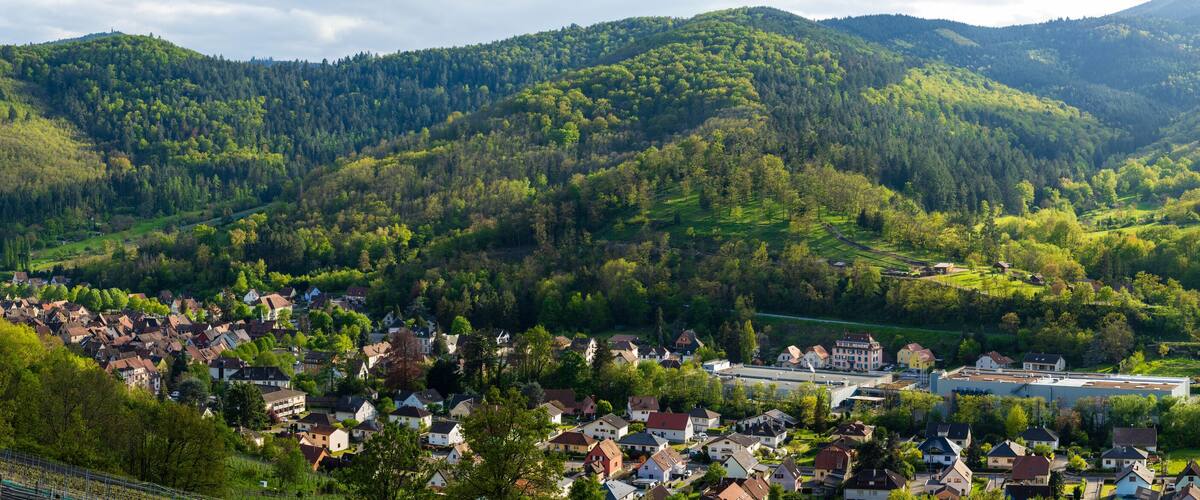 A village nestled in a valley surrounded by forested hills.
