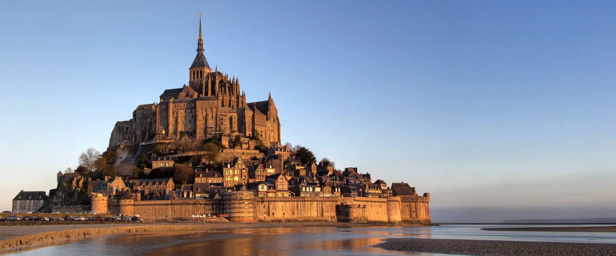A historic cathedral with a tall spire, situated on a hill overlooking a river.