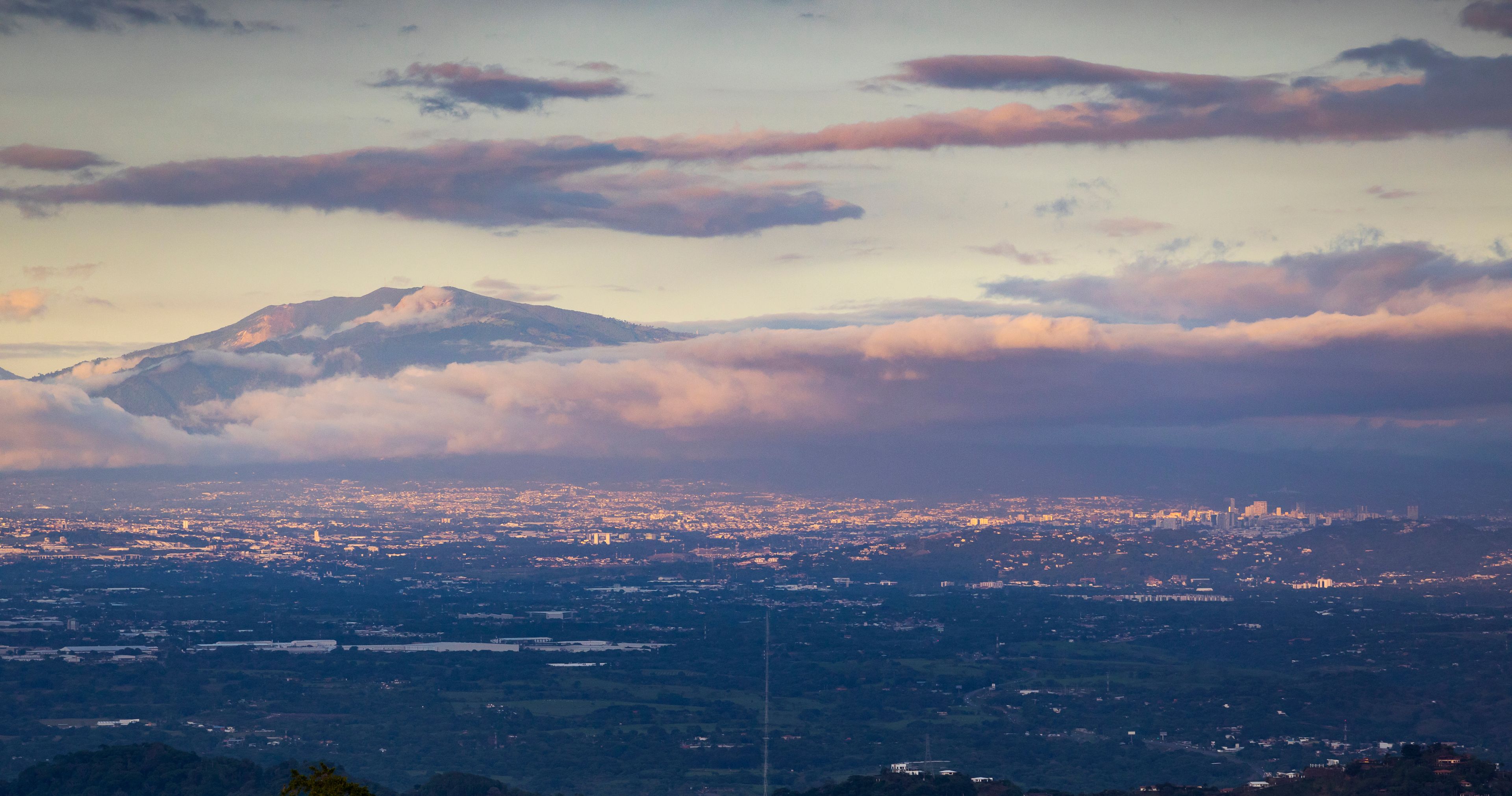 Cordillera con nubes, una ciudad debajo y cielo despejado.