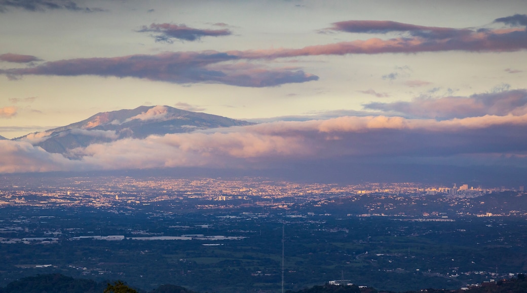 Cordillera con nubes, una ciudad debajo y cielo despejado.