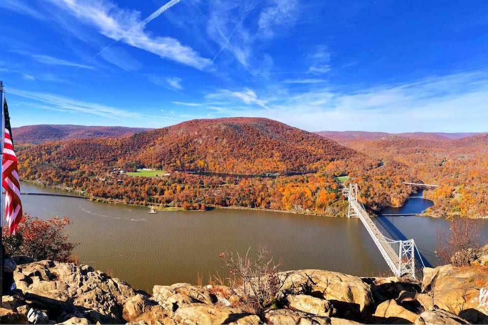 A river with a bridge, autumn foliage, and a flag.