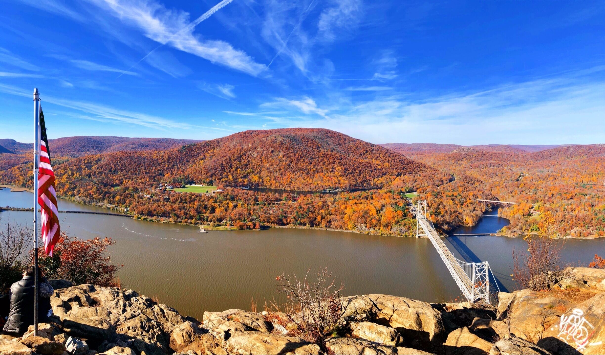 A river with a bridge, autumn foliage, and a flag.