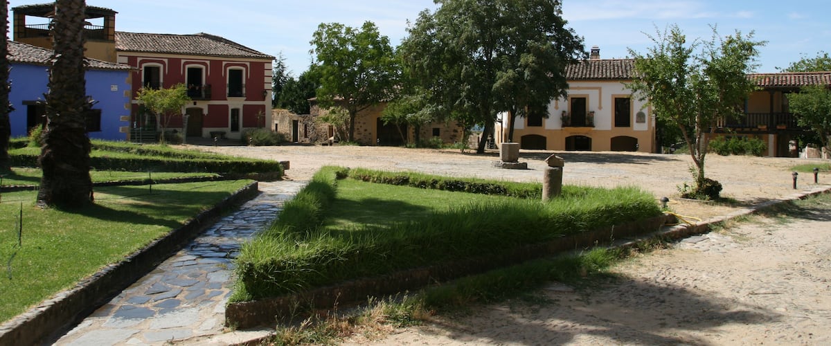 A courtyard with stone pathways, palm trees, and traditional buildings.
