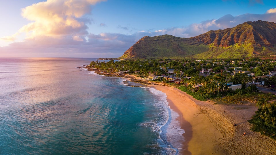 A coastal town with a beach, houses, and a mountain.