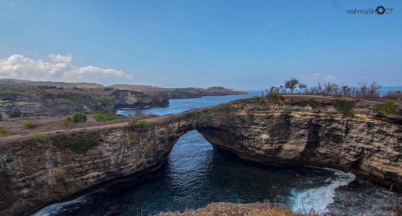 A natural rock formation with a bridge over a river.