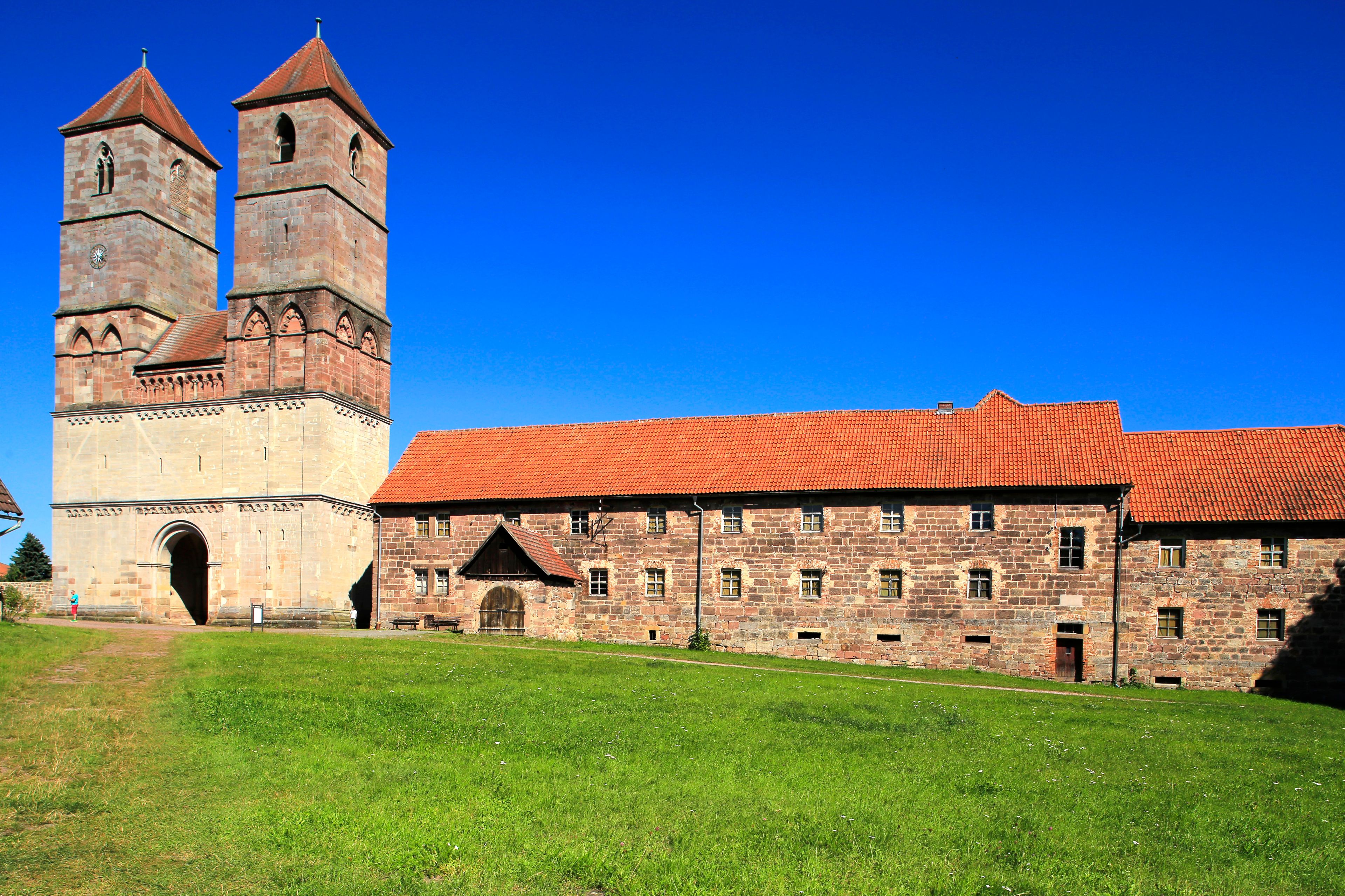 A historic building with two prominent towers and a red-tiled roof.