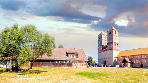 A historic church with a bell tower, surrounded by traditional buildings and open grassy areas.