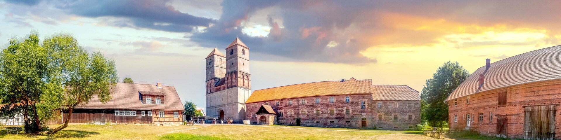 Una iglesia histórica con un campanario, rodeada de edificios tradicionales y zonas verdes.