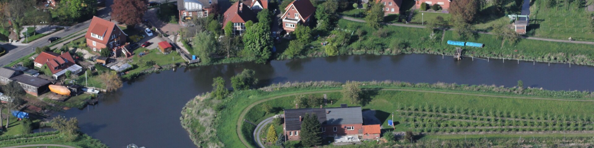 Luftaufnahme: eine Flusskurve der Lühe, dahinter die Kurze Straße in Grünendeich