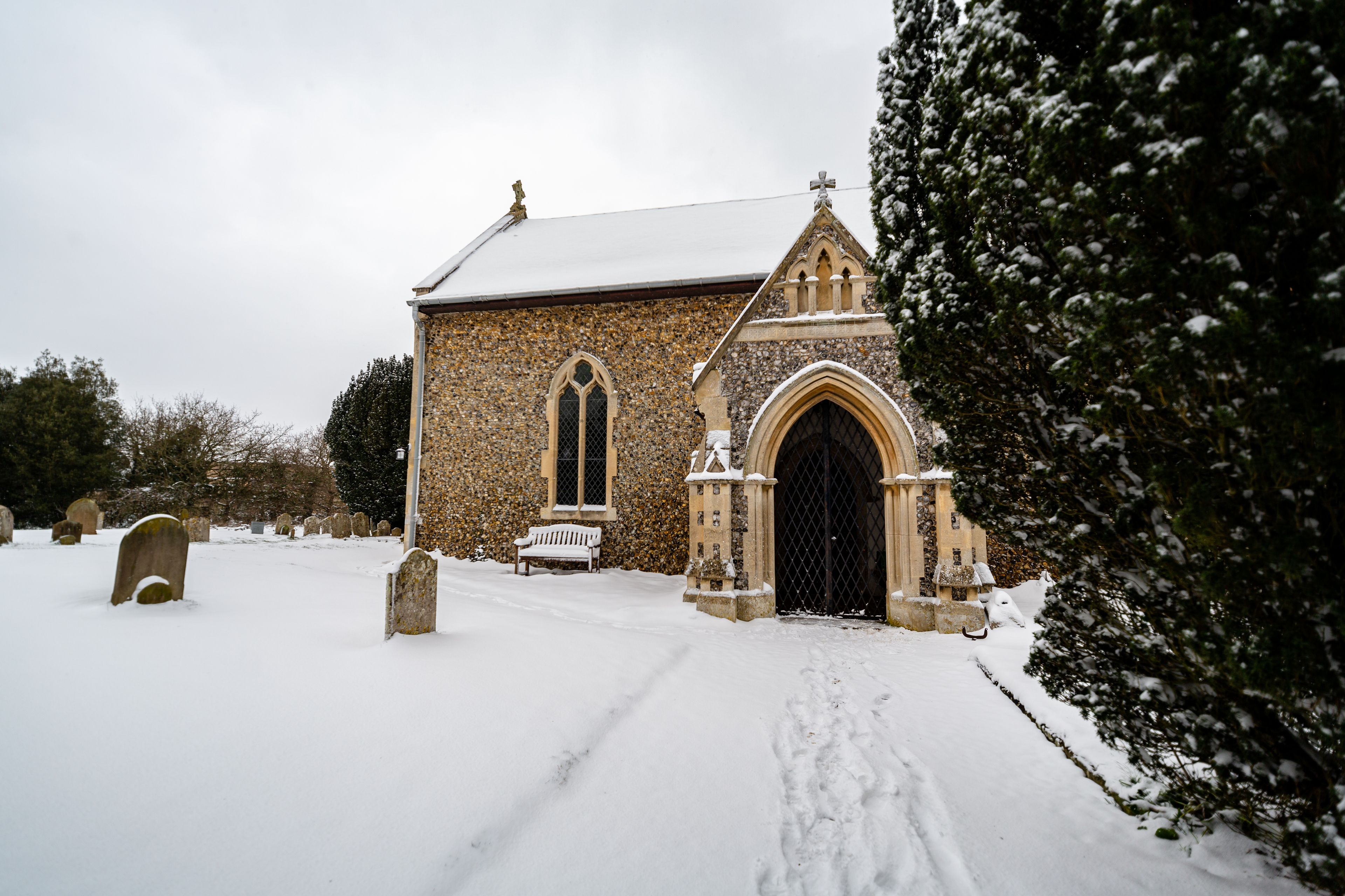 A stone church with a snow-covered roof and a large arched entrance.