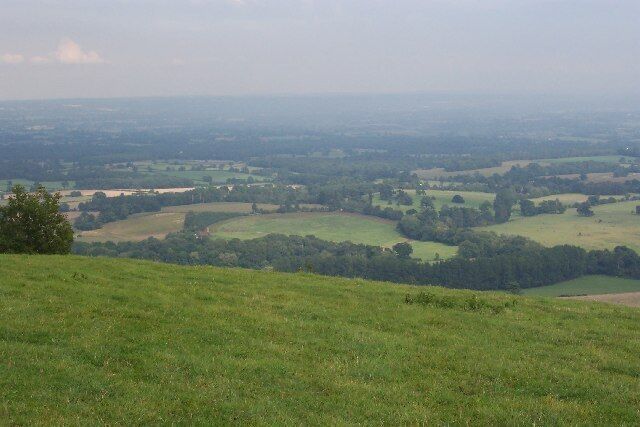 Bushovel Farm, Wiston. Formerly called Bush Hovel Farm, it is seen slightly left of centre in this picture taken from Chanctonbury Ring. What is interesting is the circular shape of the field to the right of the farmhouse and buildings (with an extension on the right). This betrays it as having been an early clearing in the vast, heavily wooded Sussex Weald from which the farm was created. There are several farms along the foot of the downs here. At first sight it appears not to the be the best situation for a farm, the southern sun being blocked by the bulk of the downs for much of the year (although not at Bushovel), but it is along this line that the chalk of the downs gives way to the gault clay of the Weald and it is here that numerous springs rise, providing a plentiful supply of water.