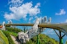 Un puente con una estructura grande que se asemeja a una mano, rodeado de vegetación y montañas.
