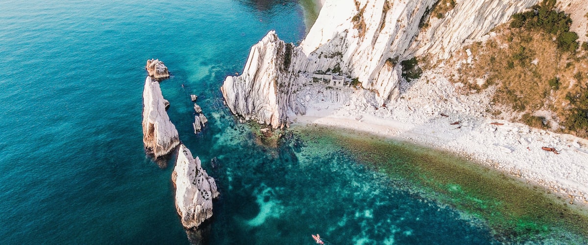 Beautiful aerial view of rocky formations in the blue water in the Beach of the Two Sisters, Italy