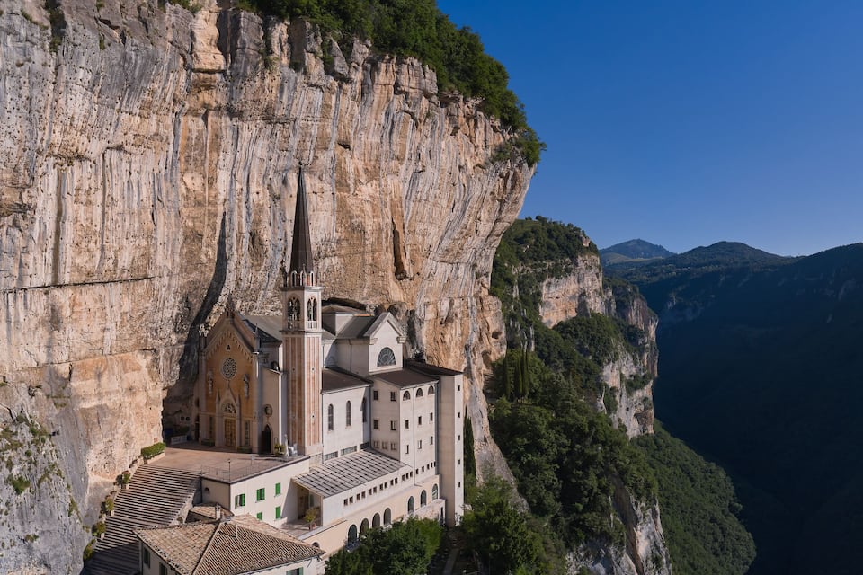 Eine Kirche, die in einen Fels gebaut ist, mit einer Berglandschaft im Hintergrund.