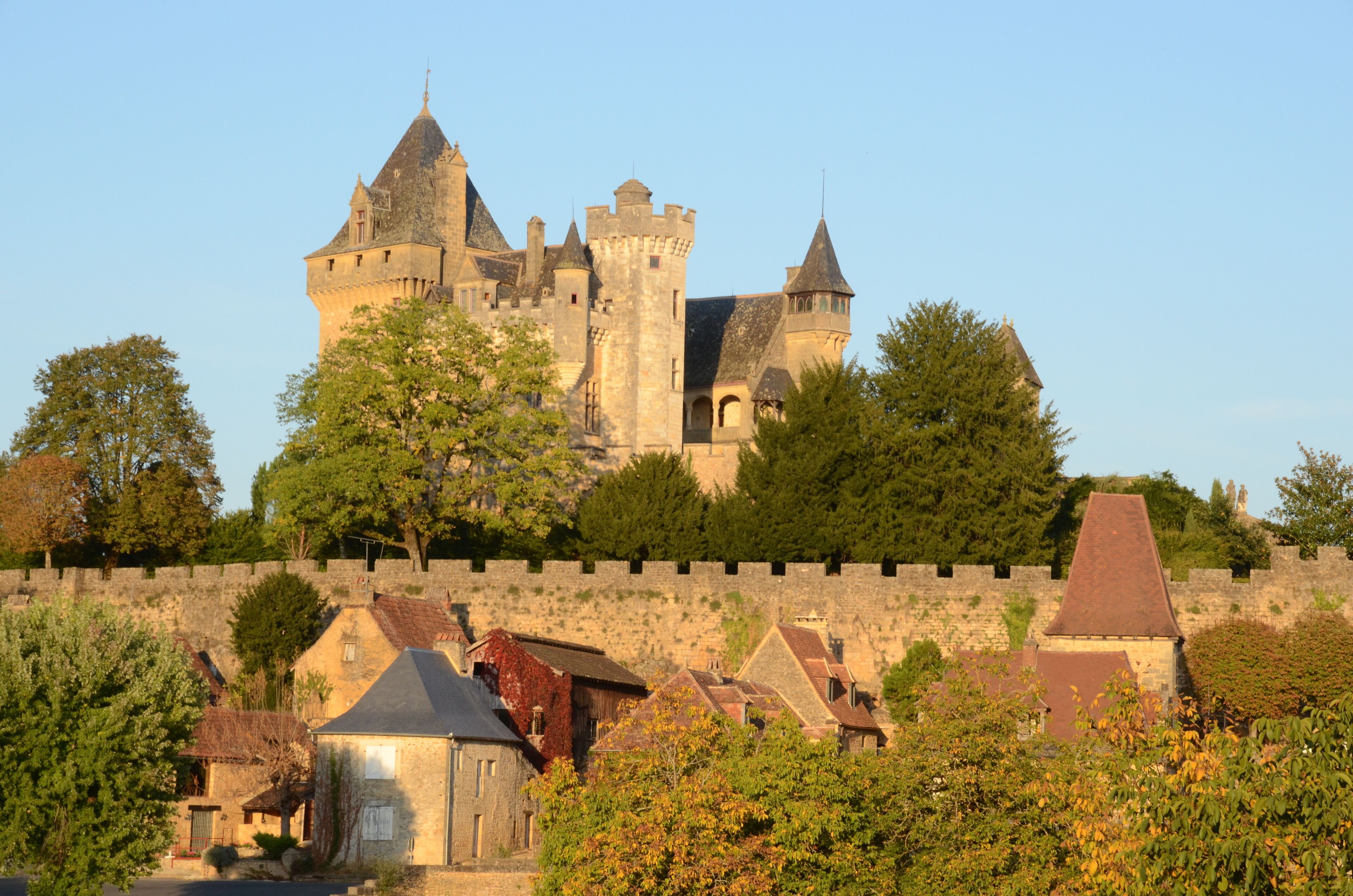 A historic castle with multiple towers and a stone wall surrounding it.