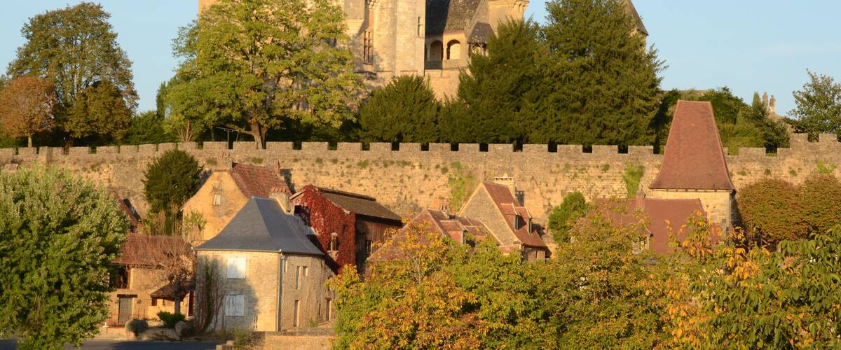 A historic castle with multiple towers and a stone wall surrounding it.