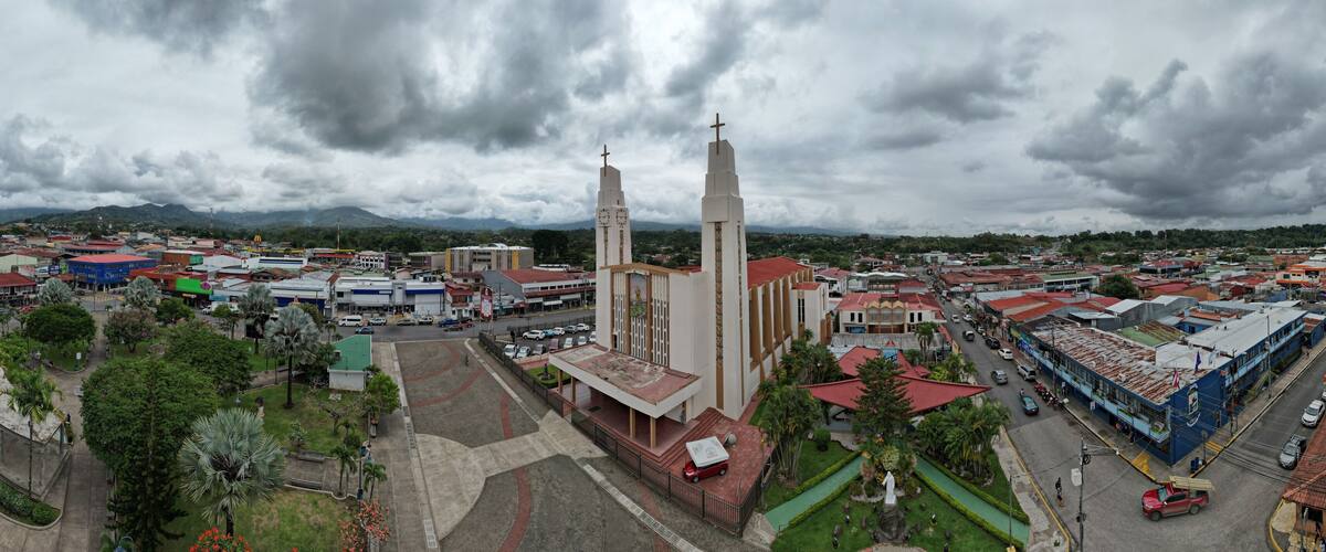 A cityscape with a prominent church featuring two tall towers and a statue in front.