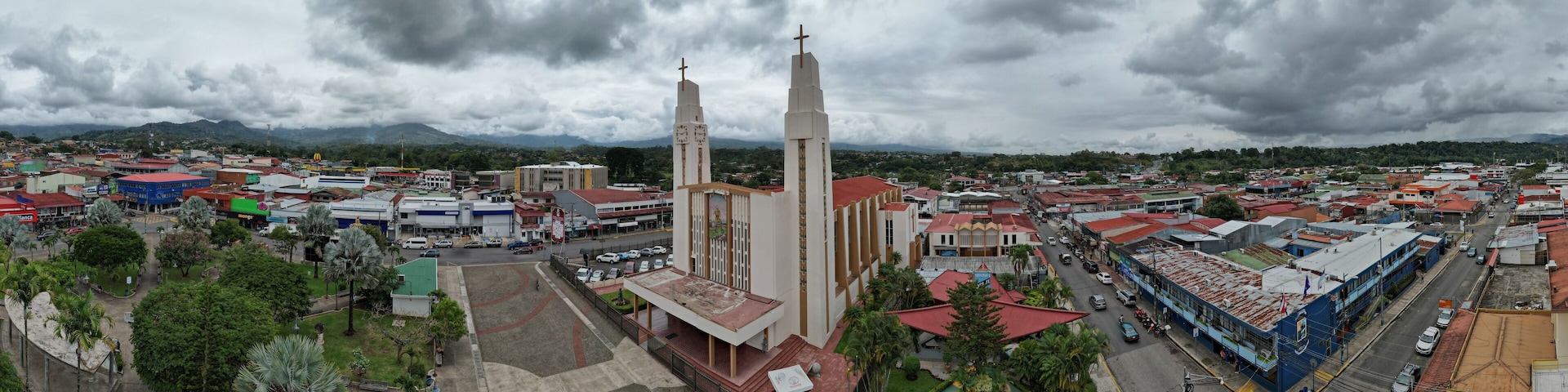A cityscape with a prominent church featuring two tall towers and a statue in front.