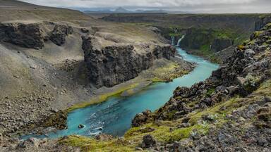Ein Fluss fließt durch eine zerklüftete Schlucht mit Wasserfällen.