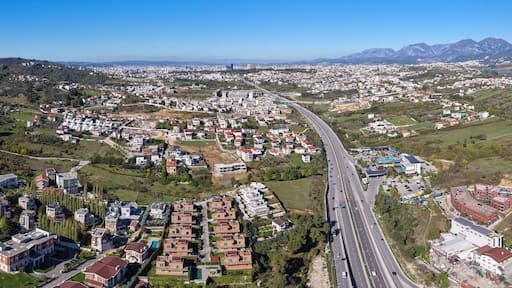 Panoramic aerial view of Tirana–Elbasan Highway through Sauk and Farkë showing Tirana’s urban expansion toward the east.