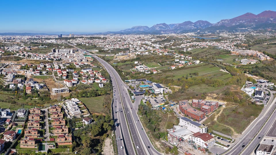 Panoramic aerial view of Tirana–Elbasan Highway through Sauk and Farkë showing Tirana’s urban expansion toward the east.