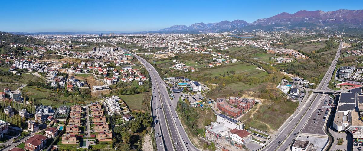 A cityscape with a highway, residential areas, and mountains in the background.