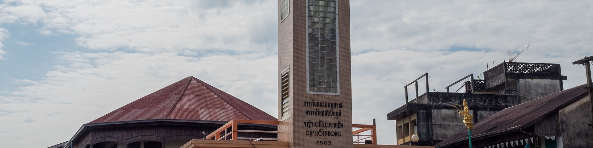A clock tower with a sign in a town square.